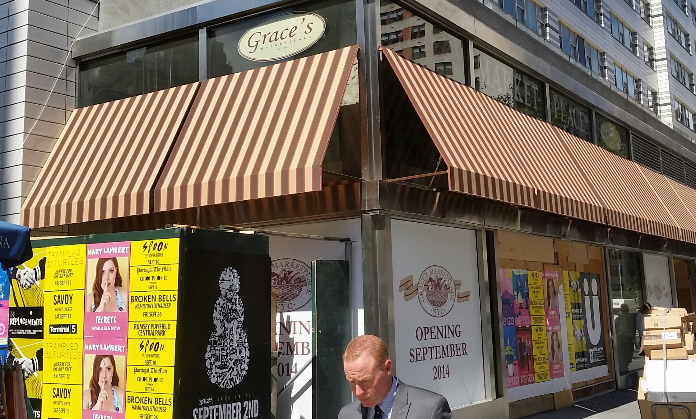 Custom striped awning across a corner storefront — Striped corner awning